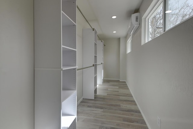 interior space with an AC wall unit, recessed lighting, light wood-type flooring, and baseboards