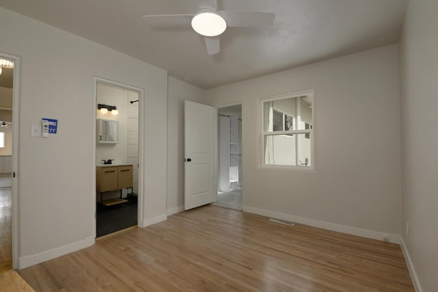 unfurnished bedroom with light wood-type flooring, baseboards, visible vents, and ensuite bathroom