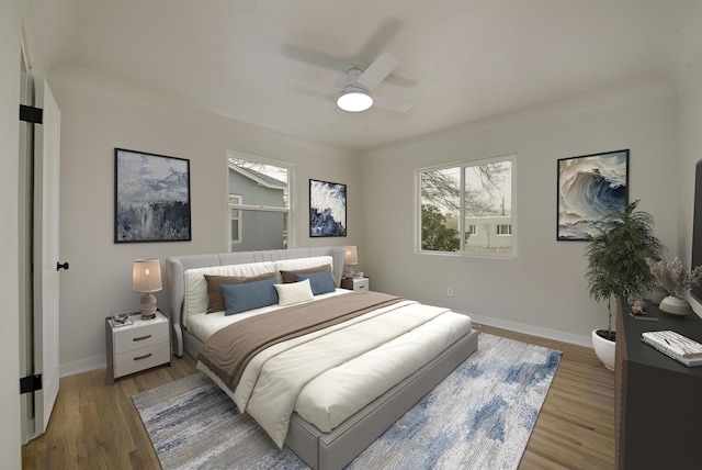 bedroom featuring ceiling fan, light wood-style flooring, and baseboards