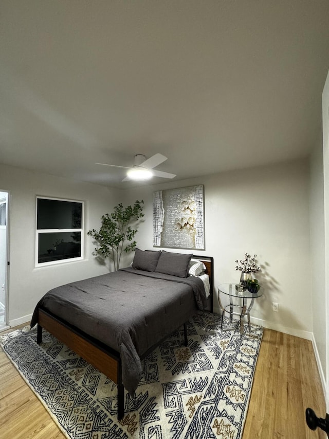 bedroom with ceiling fan, wood finished floors, and baseboards