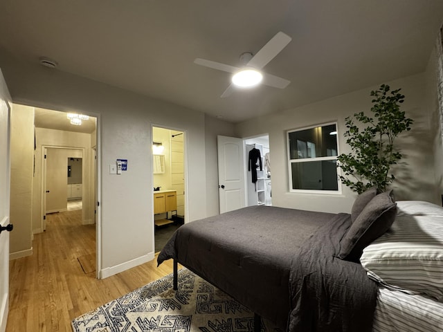 bedroom with ensuite bathroom, baseboards, a ceiling fan, and light wood-style floors