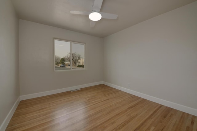 empty room featuring light wood-type flooring, visible vents, baseboards, and a ceiling fan