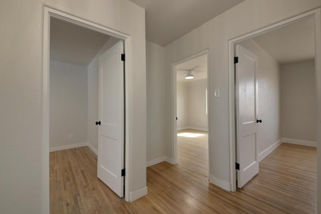 corridor with baseboards and light wood-style floors