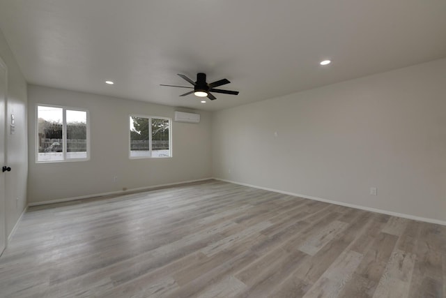 spare room with a wall unit AC, recessed lighting, a ceiling fan, baseboards, and light wood-type flooring