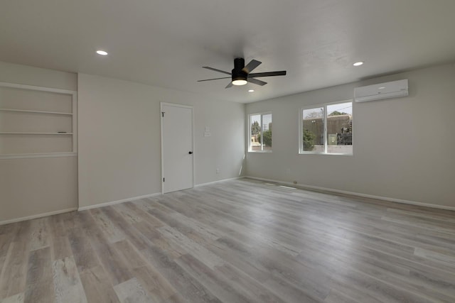 spare room featuring a wall unit AC, baseboards, wood finished floors, and recessed lighting