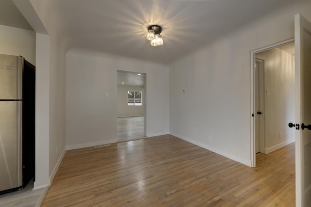 spare room featuring light wood-style floors, visible vents, and baseboards