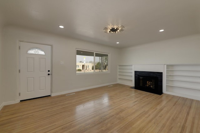 unfurnished living room featuring baseboards, light wood finished floors, a fireplace with flush hearth, and recessed lighting