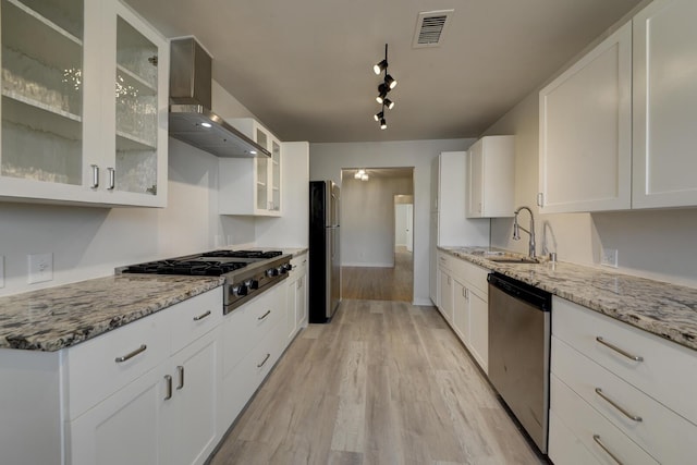 kitchen with visible vents, light wood-style flooring, stainless steel appliances, wall chimney range hood, and a sink