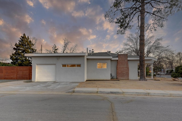 view of front of home featuring a garage, driveway, fence, and stucco siding