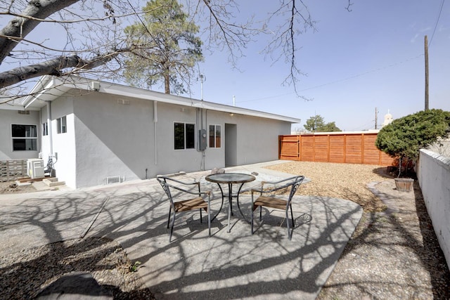 rear view of house featuring a patio area, a fenced backyard, outdoor dining space, and stucco siding