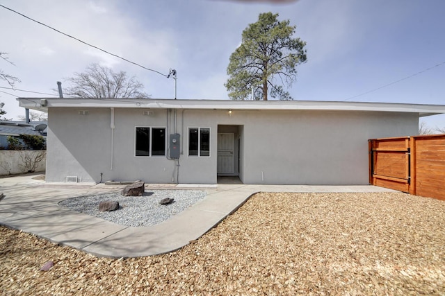 back of property featuring a gate, fence, and stucco siding