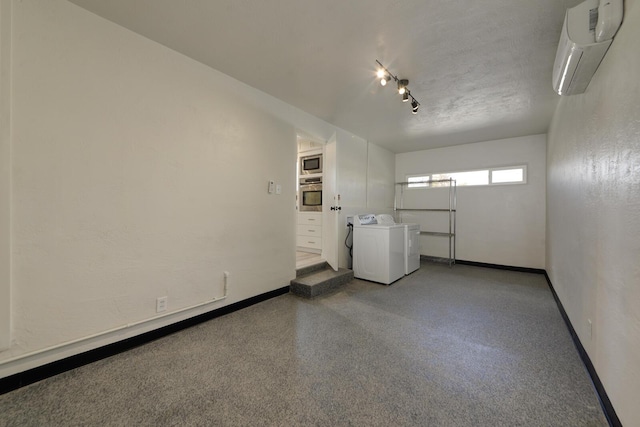 empty room featuring baseboards, an AC wall unit, speckled floor, and washer and dryer