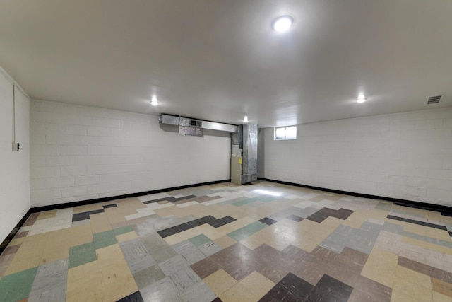 basement featuring tile patterned floors, visible vents, and concrete block wall