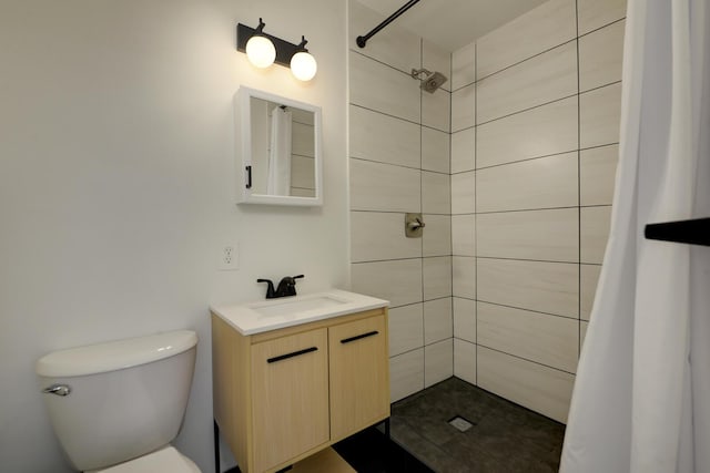 full bath featuring toilet, a tile shower, and vanity