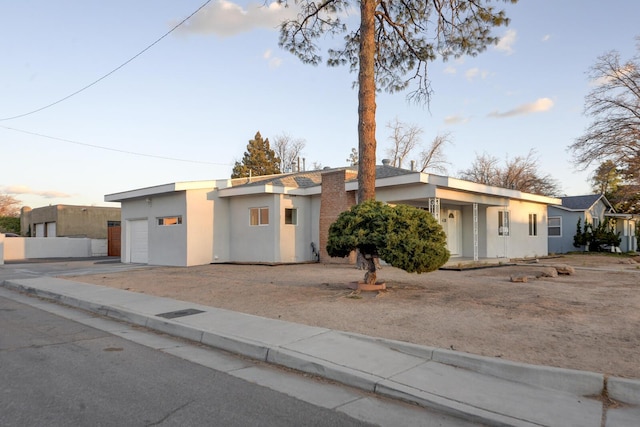 view of front of house with a garage, concrete driveway, and stucco siding