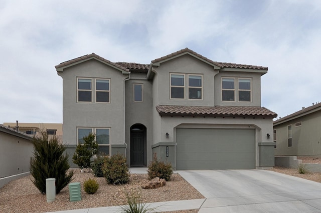 mediterranean / spanish home featuring an attached garage, a tiled roof, concrete driveway, and stucco siding