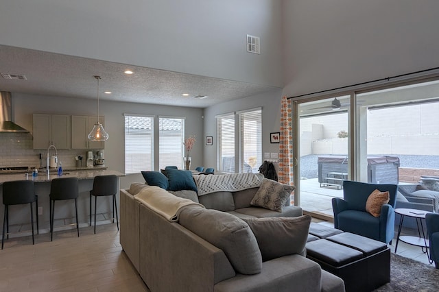 living room with light wood-style flooring, recessed lighting, visible vents, and a textured ceiling