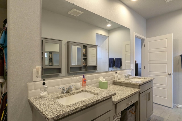 bathroom with tasteful backsplash, visible vents, vanity, and wood finished floors