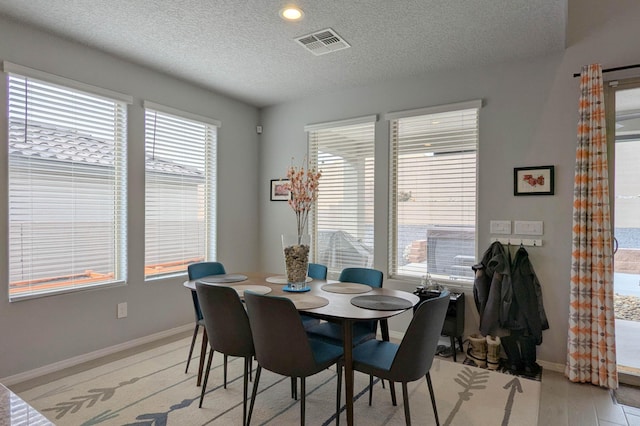 dining area featuring baseboards, visible vents, and a textured ceiling