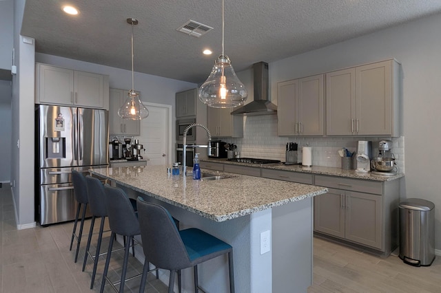 kitchen featuring stainless steel appliances, tasteful backsplash, visible vents, gray cabinetry, and wall chimney exhaust hood