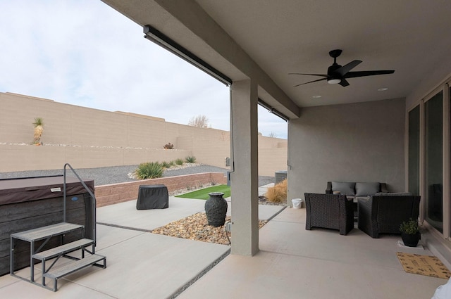 view of patio featuring a hot tub, a fenced backyard, ceiling fan, and outdoor lounge area