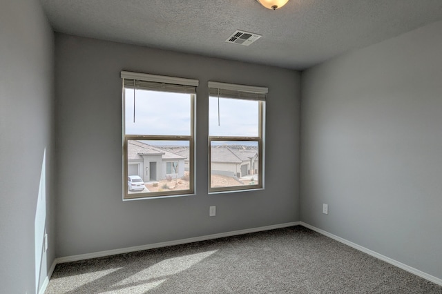 empty room with visible vents, a textured ceiling, baseboards, and carpet flooring