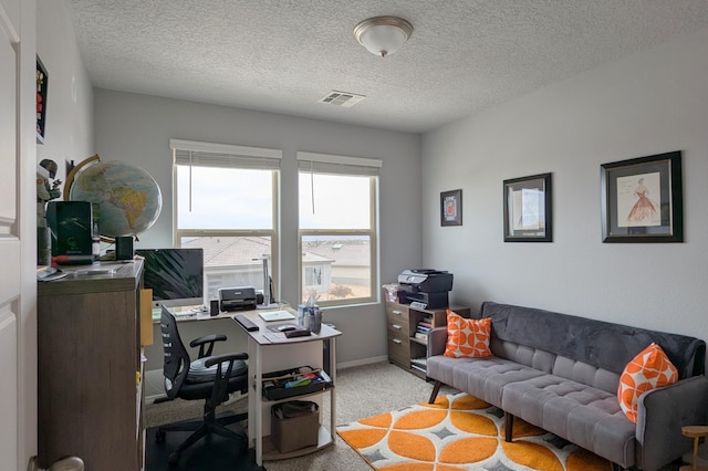 home office featuring baseboards, visible vents, a textured ceiling, and light colored carpet