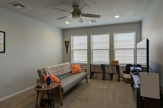 carpeted office space featuring a textured ceiling, baseboards, visible vents, and a ceiling fan