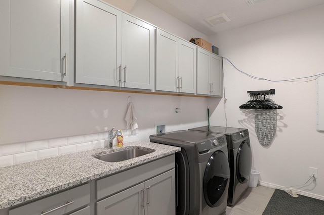 clothes washing area featuring baseboards, a sink, cabinet space, and washer and dryer