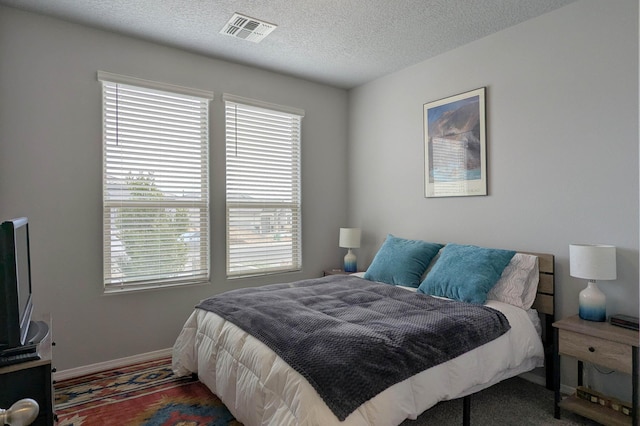 bedroom with baseboards, multiple windows, visible vents, and a textured ceiling