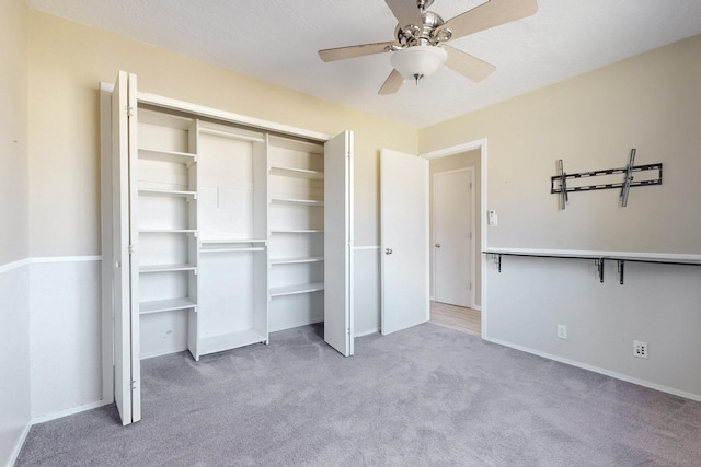 unfurnished bedroom featuring carpet floors, a closet, baseboards, and a ceiling fan