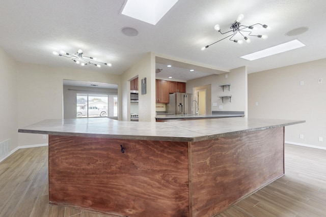 kitchen featuring a skylight, light wood-style flooring, and stainless steel appliances