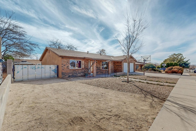 single story home featuring a garage, driveway, a gate, and brick siding