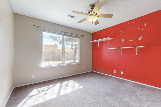 empty room with carpet, visible vents, baseboards, and a textured ceiling