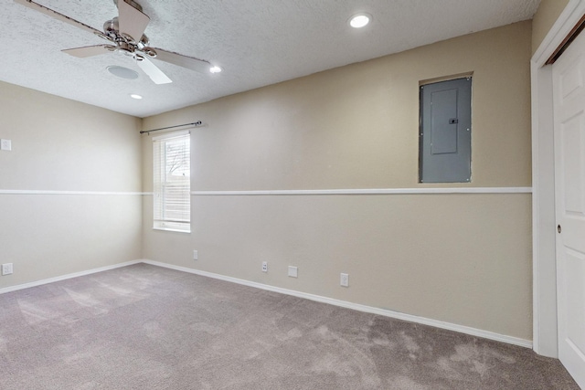 carpeted spare room with recessed lighting, a ceiling fan, a textured ceiling, electric panel, and baseboards