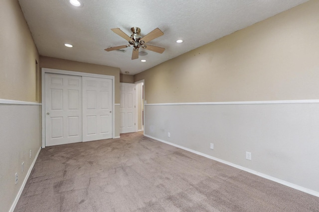 unfurnished bedroom featuring baseboards, carpet, a textured ceiling, a closet, and recessed lighting