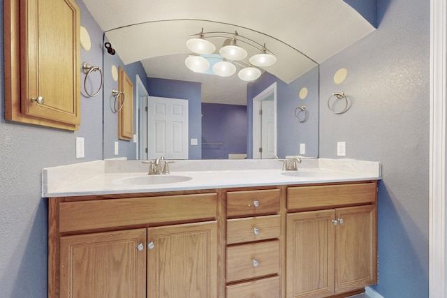 bathroom with a textured wall, a sink, and double vanity