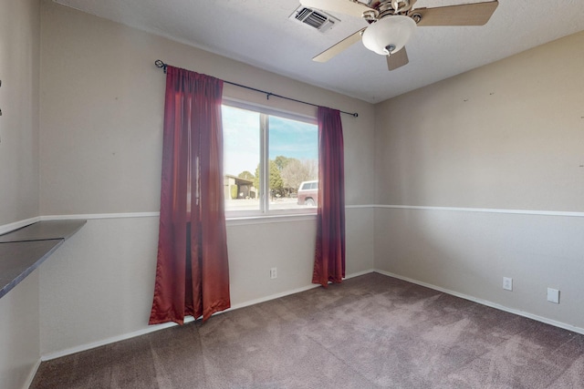 unfurnished room with carpet floors, baseboards, visible vents, and a ceiling fan