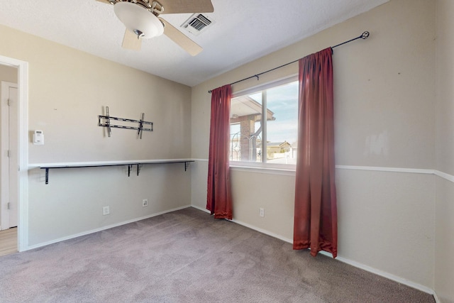 spare room featuring carpet, visible vents, ceiling fan, and baseboards