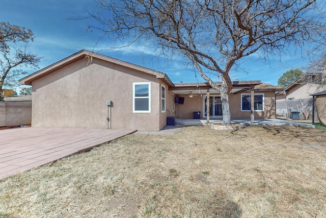 back of house with a yard, a patio area, fence, and stucco siding