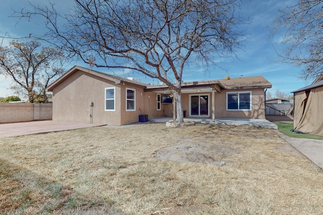 rear view of property with a patio area, fence, and stucco siding