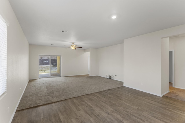 spare room with a ceiling fan, visible vents, baseboards, and wood finished floors