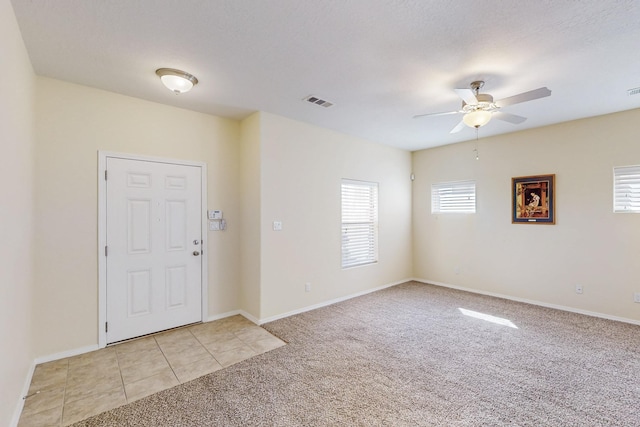 entrance foyer with ceiling fan, light tile patterned floors, light carpet, visible vents, and baseboards