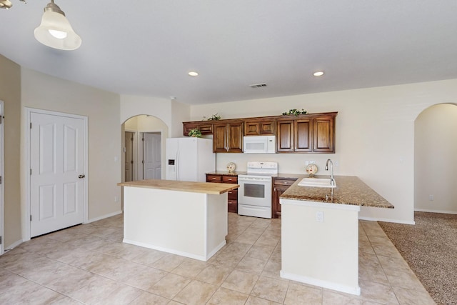 kitchen with arched walkways, white appliances, a sink, and visible vents