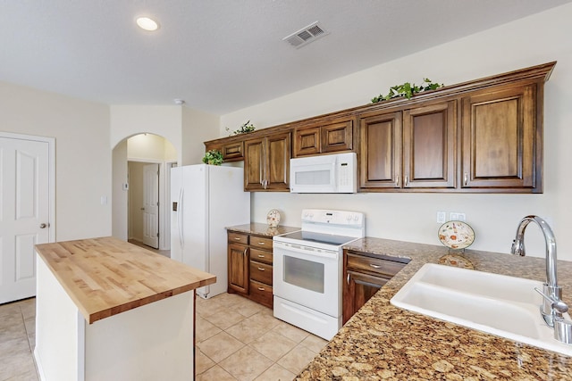 kitchen with white appliances, visible vents, wood counters, a center island, and a sink