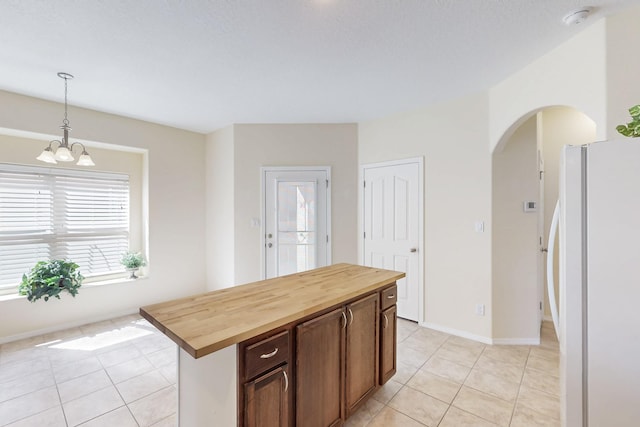 kitchen featuring wooden counters, light tile patterned flooring, and freestanding refrigerator