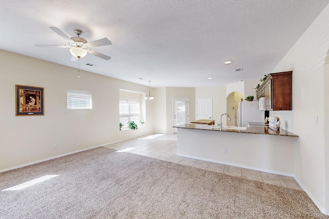 kitchen with arched walkways, light tile patterned floors, light colored carpet, white appliances, and visible vents