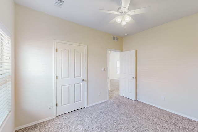 unfurnished bedroom with carpet floors, multiple windows, and visible vents