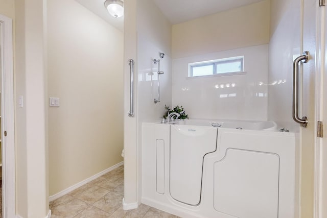 bathroom featuring tile patterned floors, baseboards, and a bath