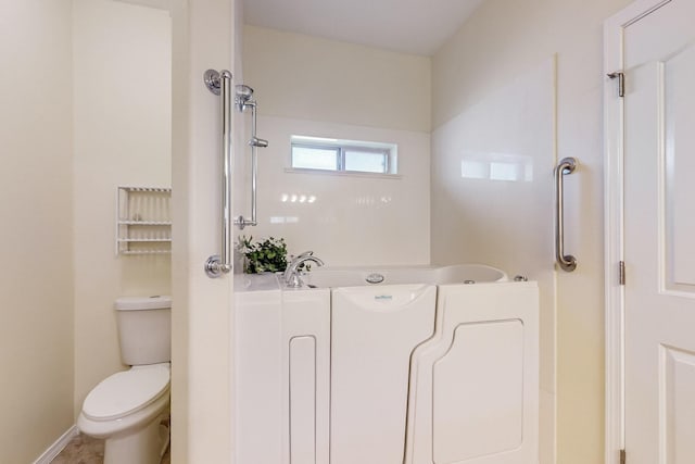 bathroom with a bathtub, baseboards, and toilet